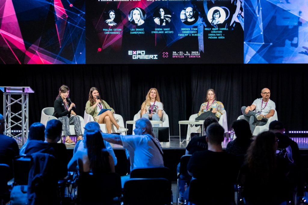 Five panelists sit in white chairs on a stage, microphones in hand, with a colorful expo banner on a screen behind them.