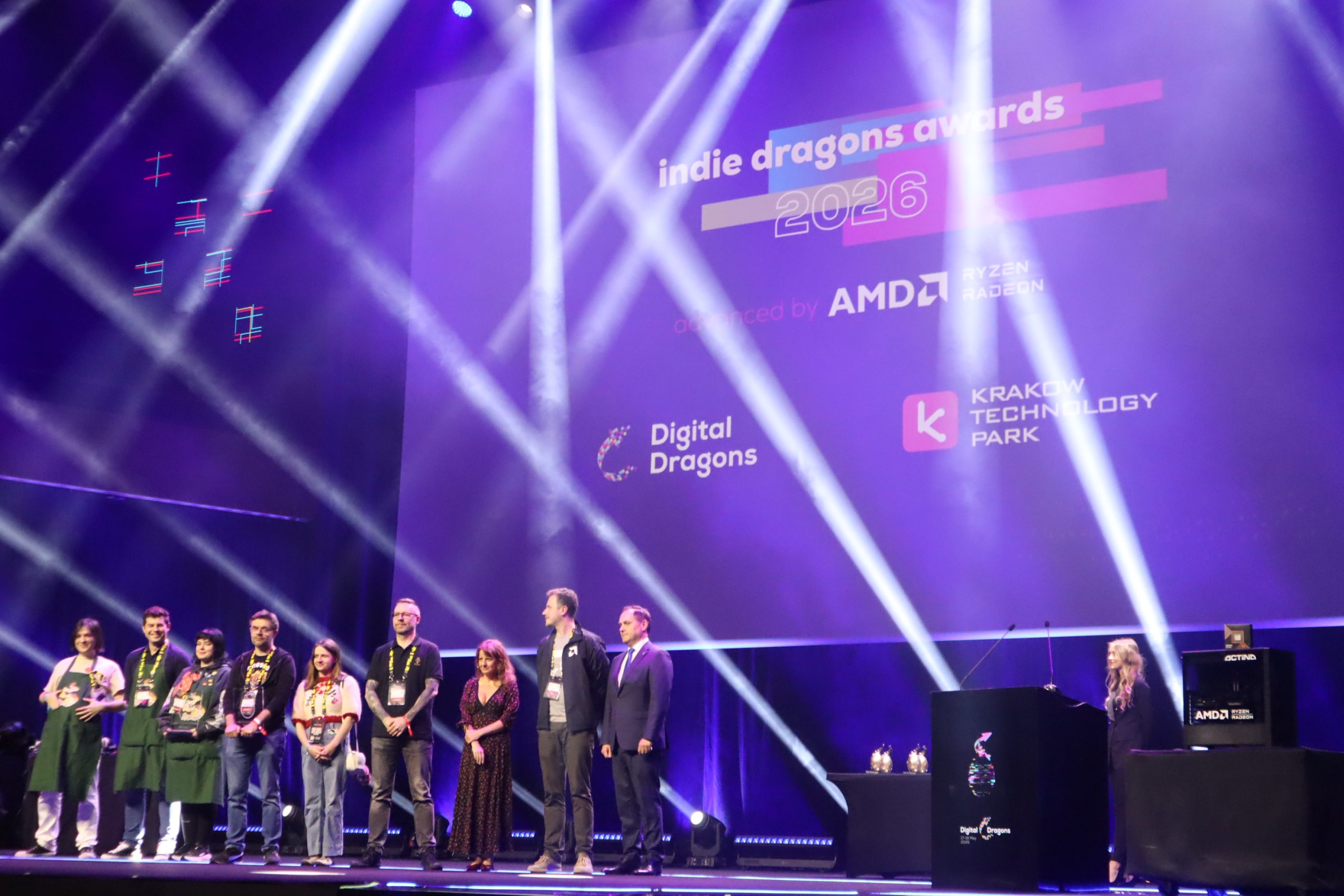 Group of award recipients on stage posing at the Indie Dragons Awards 2026 with purple lighting in the background.