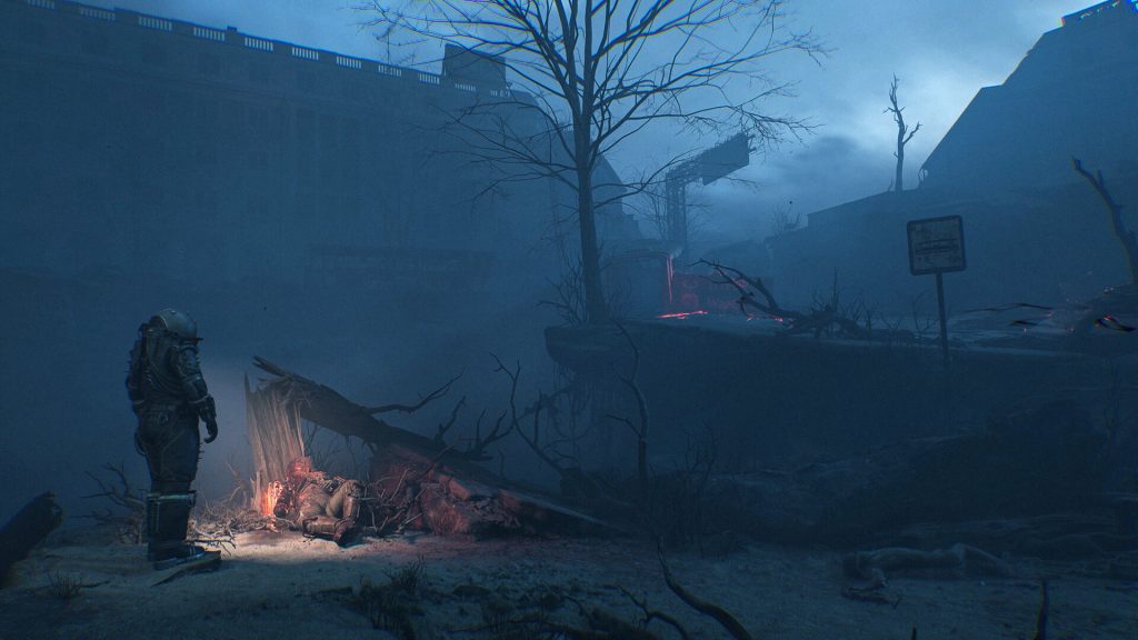 Astronaut in armor stands by a small fire among rubble in a desolate, blue-tinted wasteland.